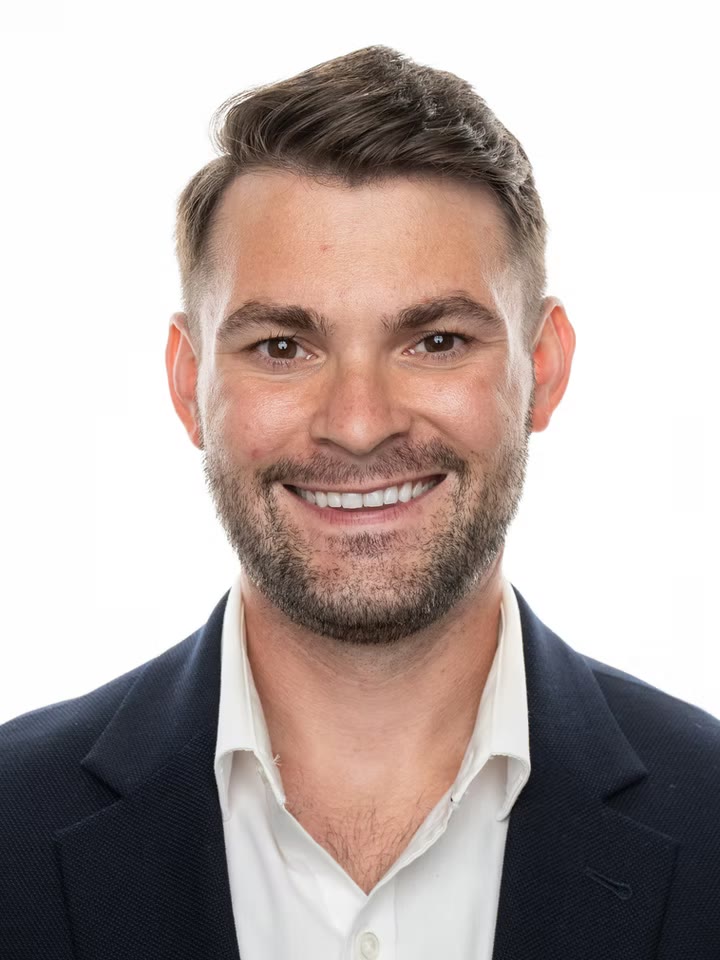 Smiling business headshot, navy blazer on white