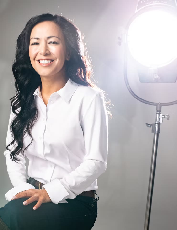Editorial portrait beside a studio light, white shirt
