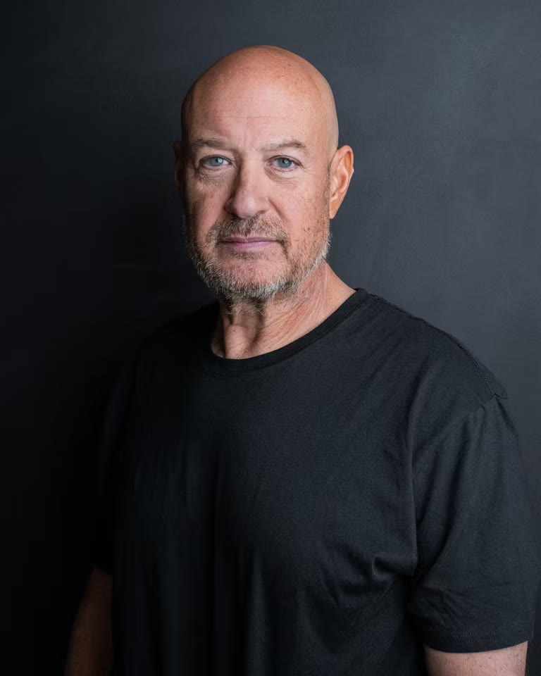 Smiling actor headshot on mid grey, black tee