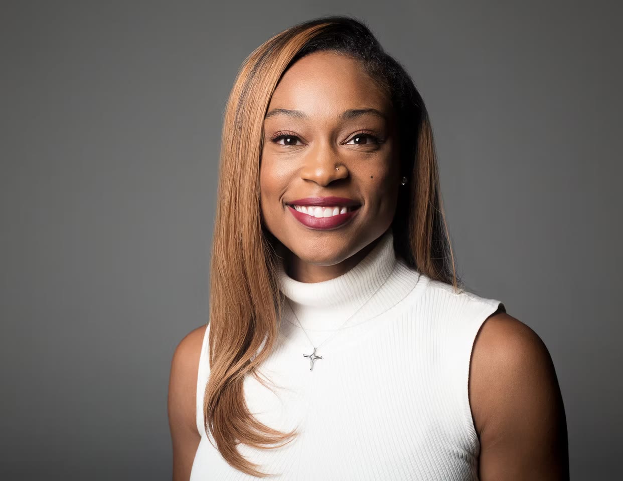 Smiling headshot on soft grey, white turtleneck