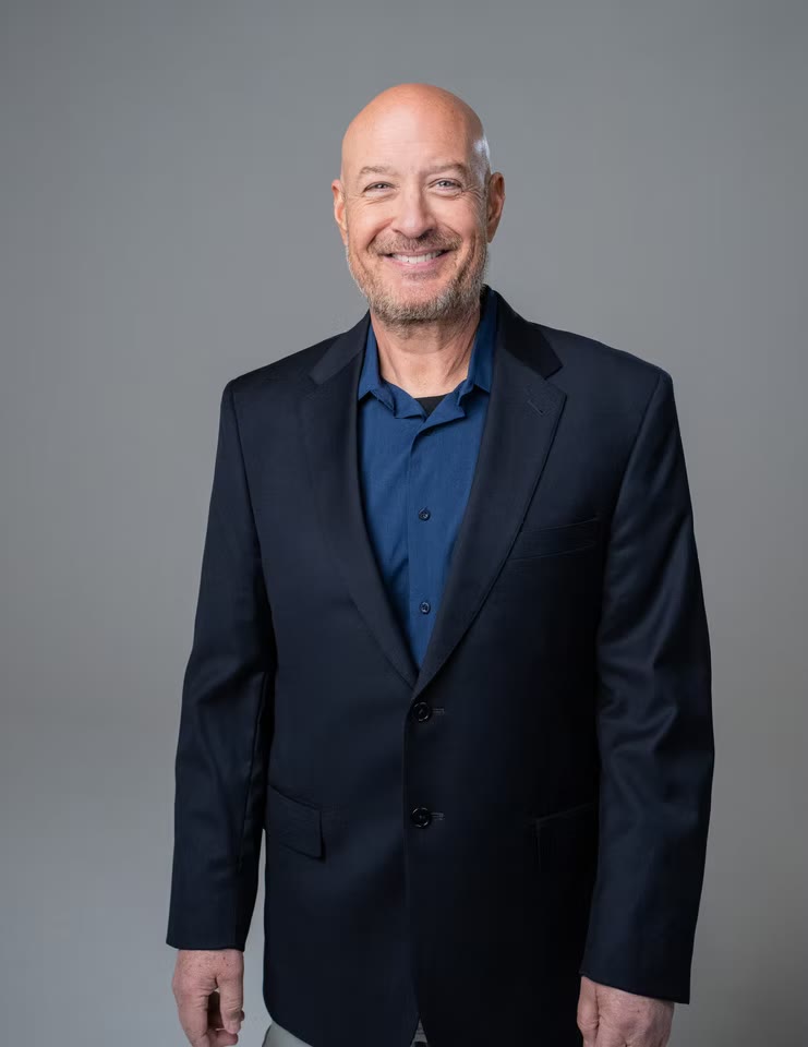 Corporate headshot in grey jacket, glasses